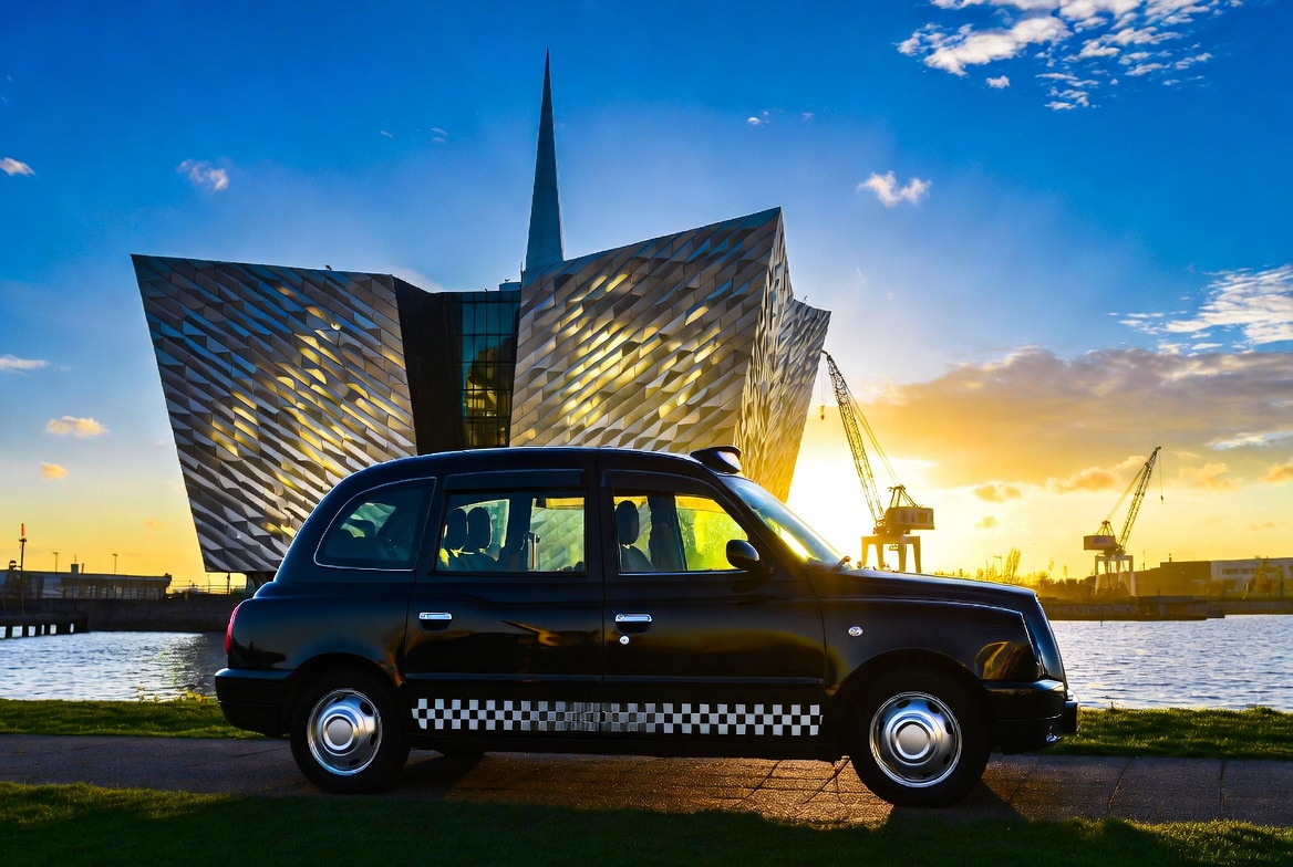 Black taxi parked at Titanic Belfast at golden sunset