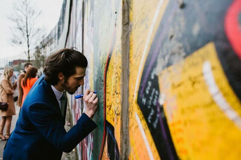 Visitor signing their name and a message of peace on the Belfast Peace Wall